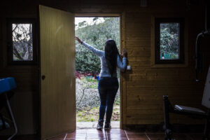 Mujer en la puerta de una casa de espaldas
